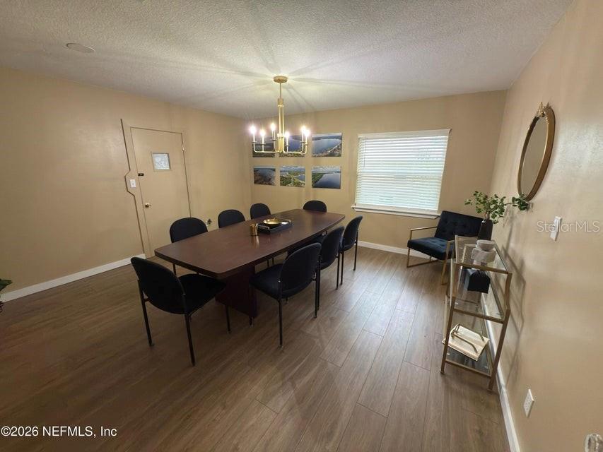 A dining room features a long wooden table, eight chairs, a chandelier, and wood-look flooring — 160 SW NIGHTINGALE STREET, KEYSTONE HEIGHTS, FL