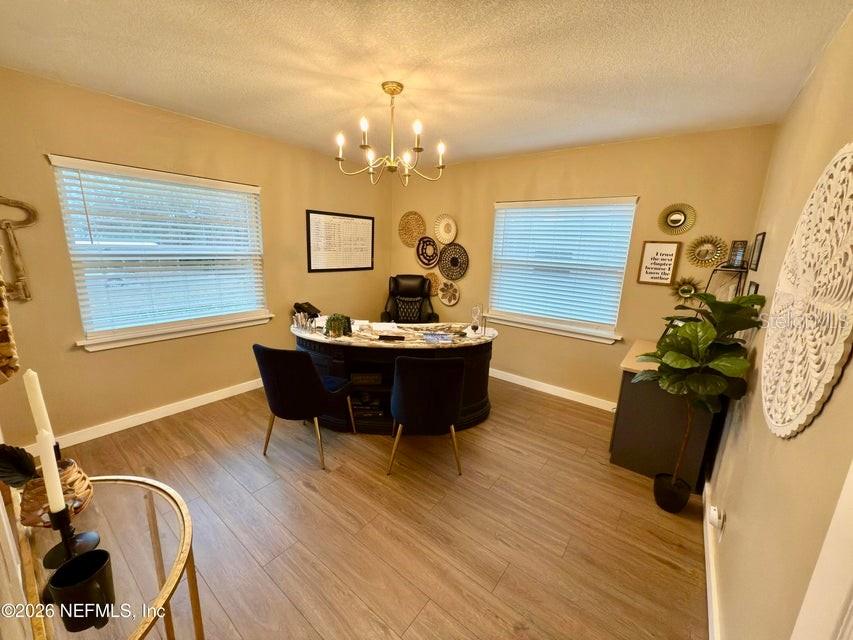 A home office features a dark curved desk, two chairs, and wood-look flooring — 160 SW NIGHTINGALE STREET, KEYSTONE HEIGHTS, FL