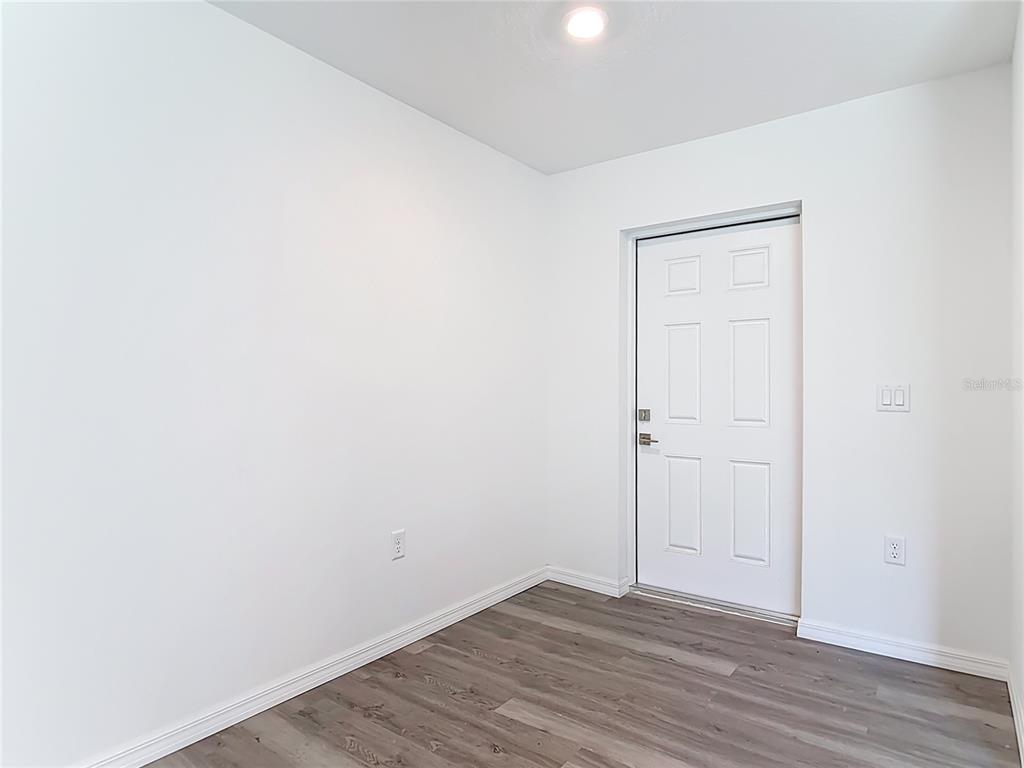 A room with white walls, wood-look flooring, and a white six-panel door — 3067 QUARTER STREET, NORTH PORT, FL