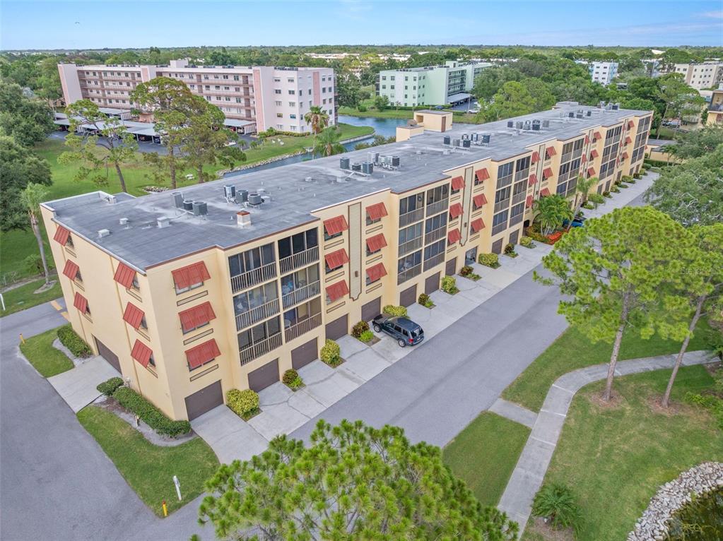 An aerial view of a multi-story apartment building with red shutters and attached garages — 5817 PARK STREET N UNIT 302, ST PETERSBURG, FL