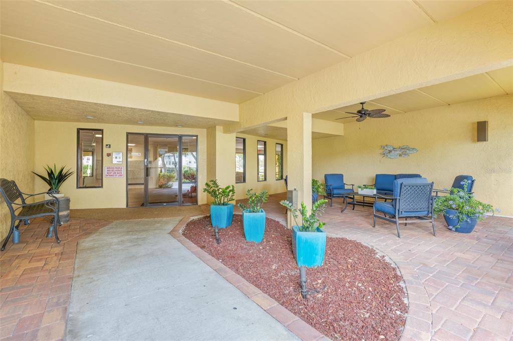 A covered outdoor entrance area features a paved walkway, blue planters, and patio furniture — 5817 PARK STREET N UNIT 302, ST PETERSBURG, FL