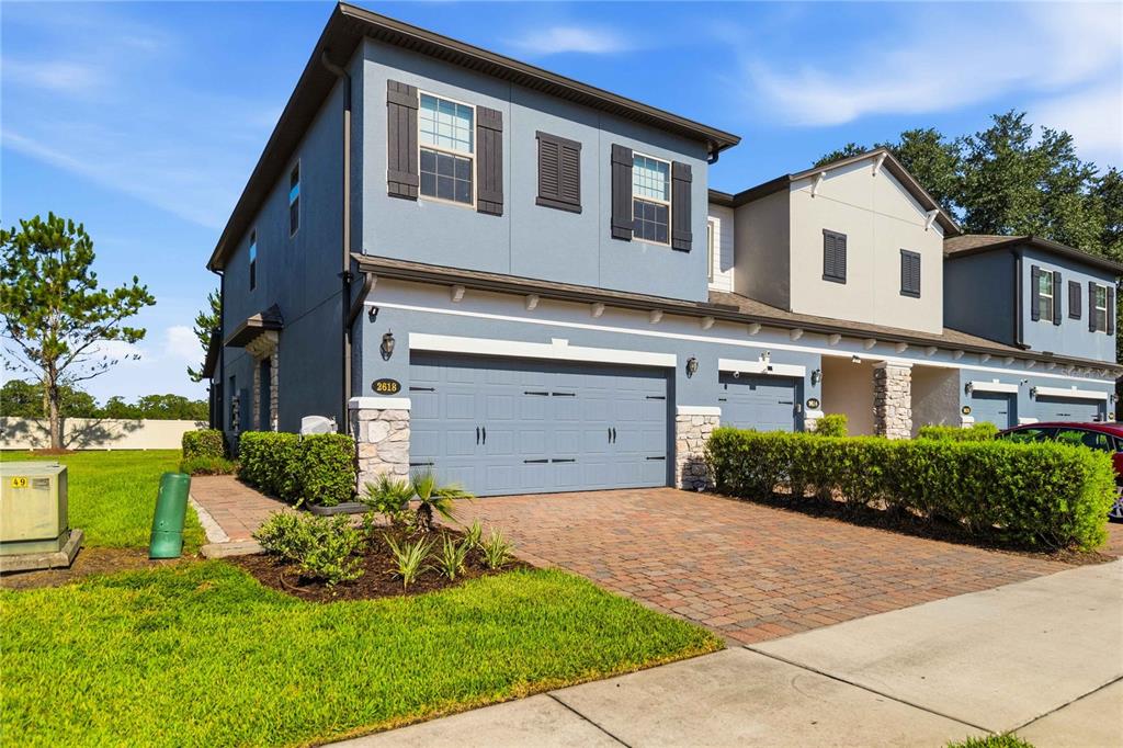 A two-story townhouse with a blue exterior, a two-car garage, and a brick driveway — 2618 WHITE ISLE LANE, ORLANDO, FL
