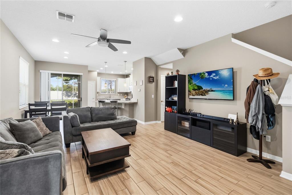 A living room features gray sofas, a coffee table, a television, and wood-look tile flooring — 2618 WHITE ISLE LANE, ORLANDO, FL
