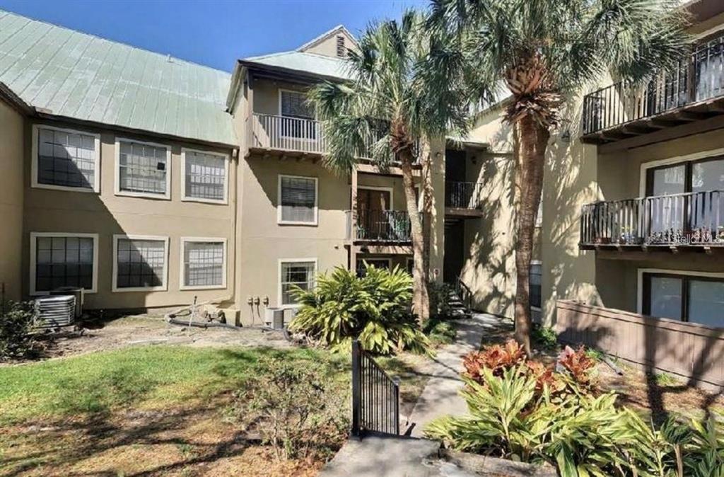 A multi-story apartment building exterior with balconies, palm trees, and a landscaped courtyard — 199 AFTON SQUARE UNIT 107, ALTAMONTE SPRINGS, FL