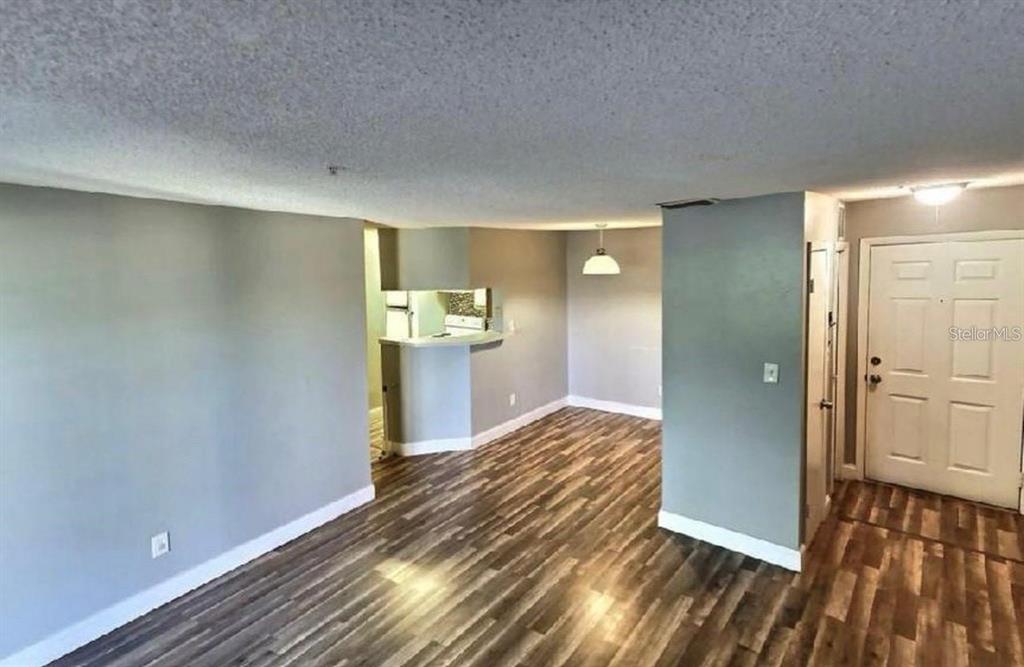 An interior view of a living area featuring wood-look flooring and a kitchen pass-through — 199 AFTON SQUARE UNIT 107, ALTAMONTE SPRINGS, FL