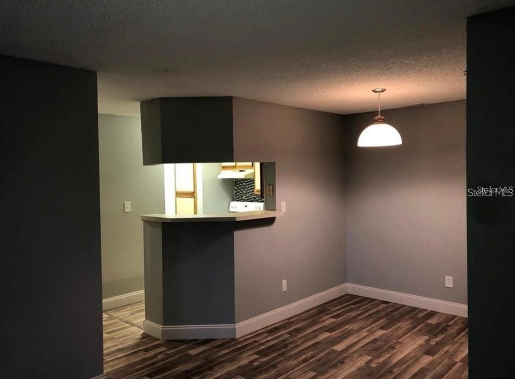 A dining area with wood-look flooring features a pass-through window to the kitchen — 199 AFTON SQUARE UNIT 107, ALTAMONTE SPRINGS, FL