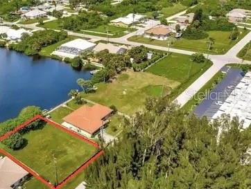 An aerial view shows a vacant, rectangular lot outlined in red next to a waterfront house — SARAGOSSA LANE, NORTH PORT, FL