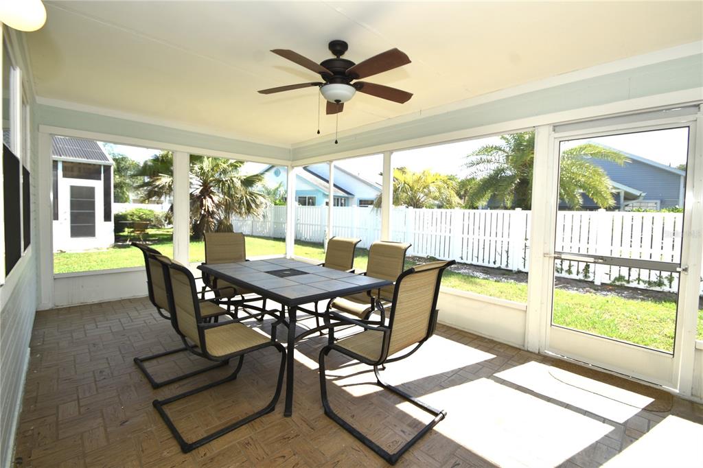 A screened-in patio features a tiled dining table, six chairs, a ceiling fan, and pavers — 34 ANDOVER DRIVE, PALM COAST, FL