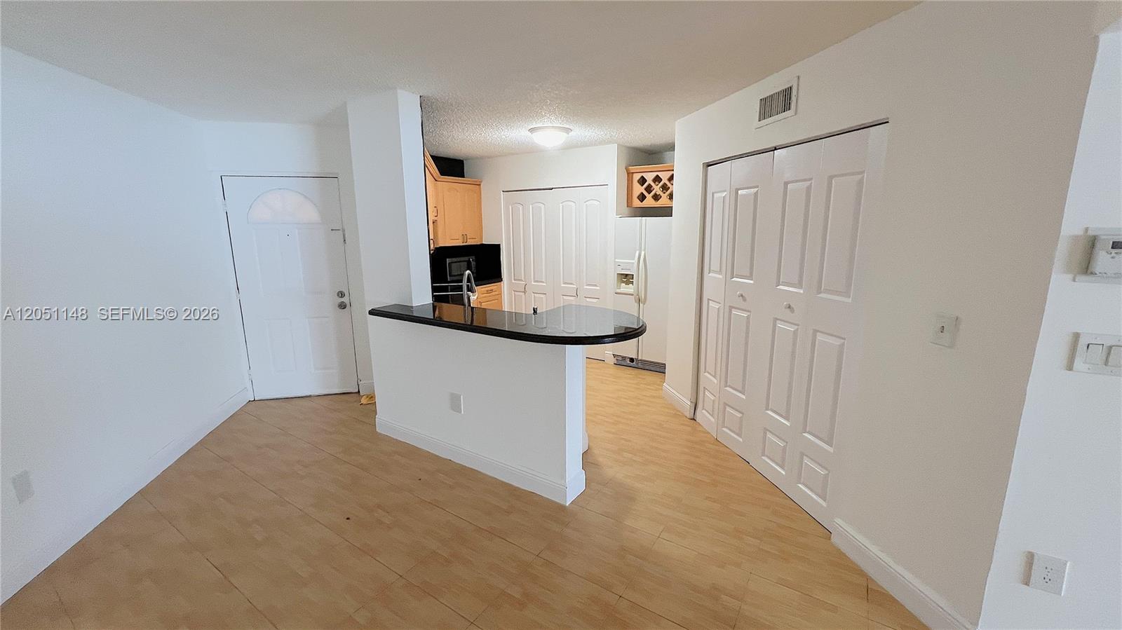 A kitchen features a black countertop breakfast bar, light wood cabinets, and white closet doors — 6272 NW 186th St # 104, Hialeah FL 33015, HIALEAH, FL