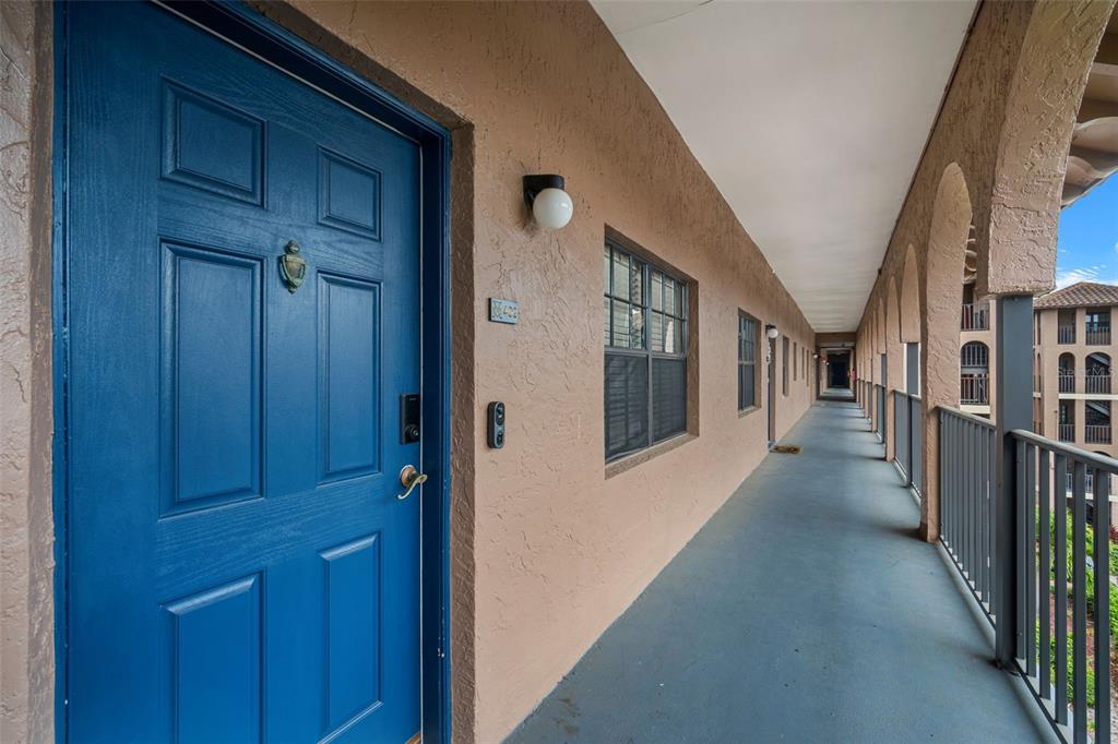 A blue front door opens onto an outdoor apartment building walkway with arched railings — 6100 GULFPORT BOULEVARD S UNIT 402, GULFPORT, FL