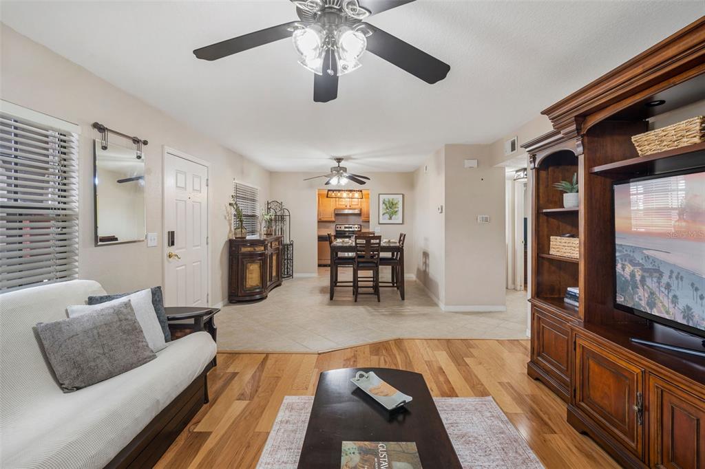 A living room with wood floors flows into a tiled dining area and kitchen — 6100 GULFPORT BOULEVARD S UNIT 402, GULFPORT, FL