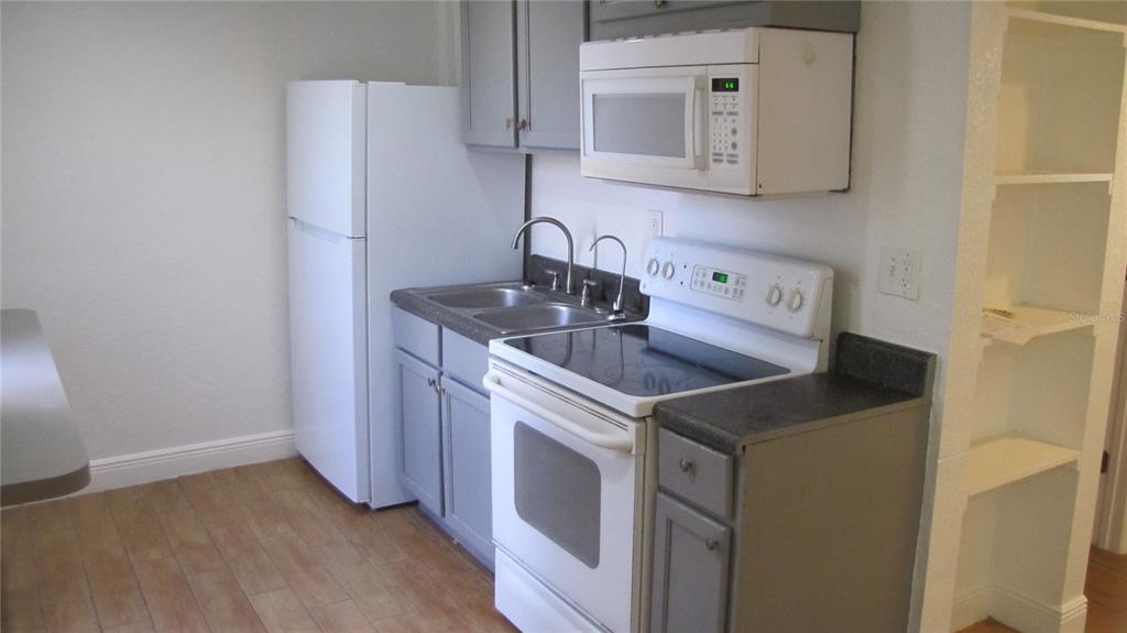 A kitchen features gray cabinets, white appliances, a double sink, and light wood-look flooring — 109 E GLADYS STREET UNIT D, TAMPA, FL