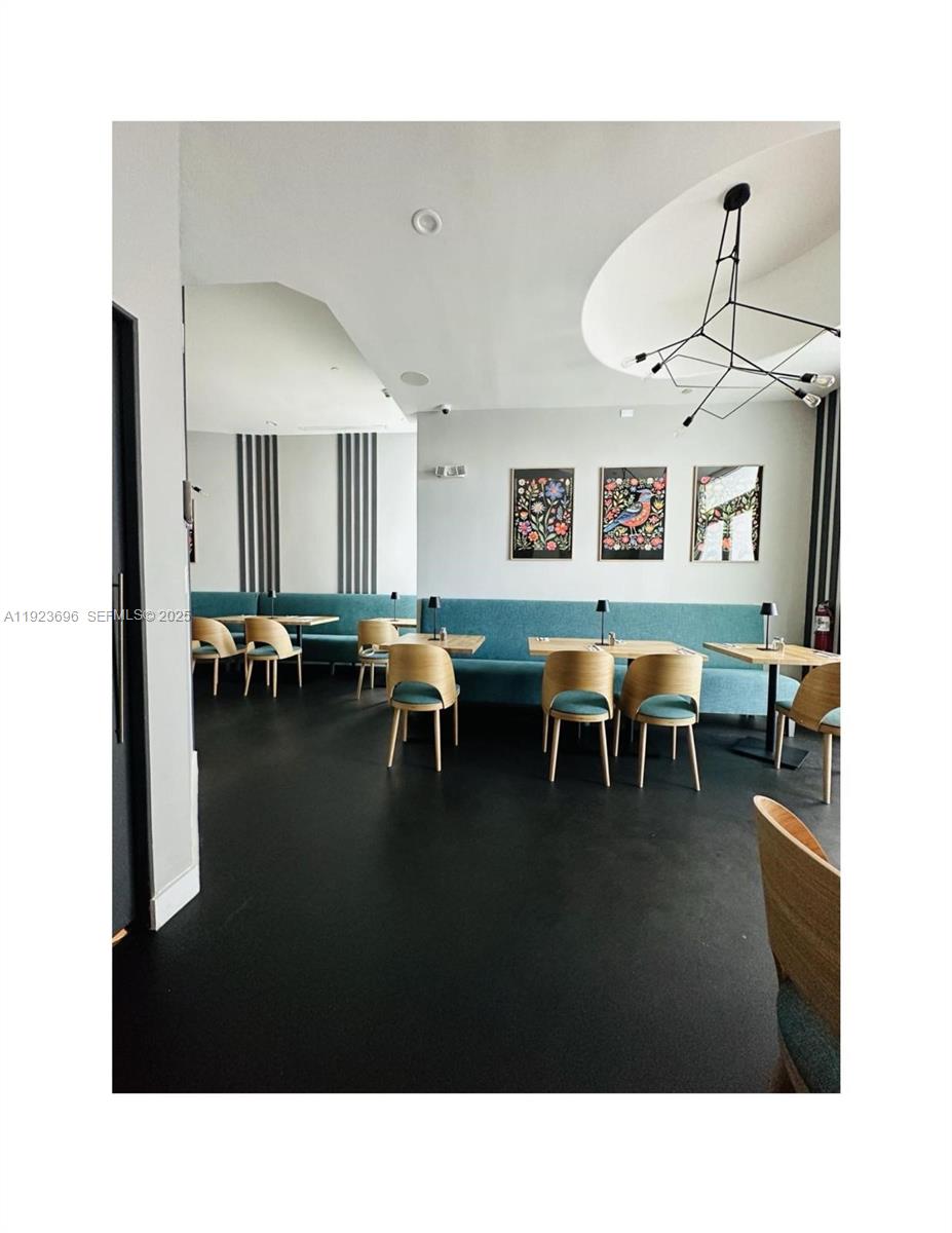 A restaurant dining area features light wood chairs, teal banquette seating, and modern light fixtures — Downtown Miami, Miami FL 33132, MIAMI, FL
