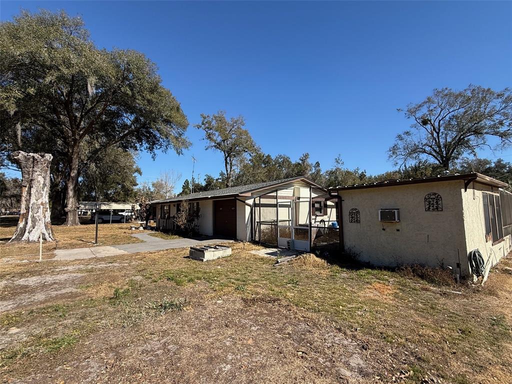 An exterior view of a single-story house with a screened porch and a detached structure — 4404 ARECA PALM DRIVE, ZEPHYRHILLS, FL