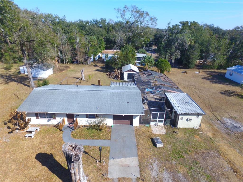 An aerial view shows a single-story house with a screened pool enclosure and detached shed — 4404 ARECA PALM DRIVE, ZEPHYRHILLS, FL