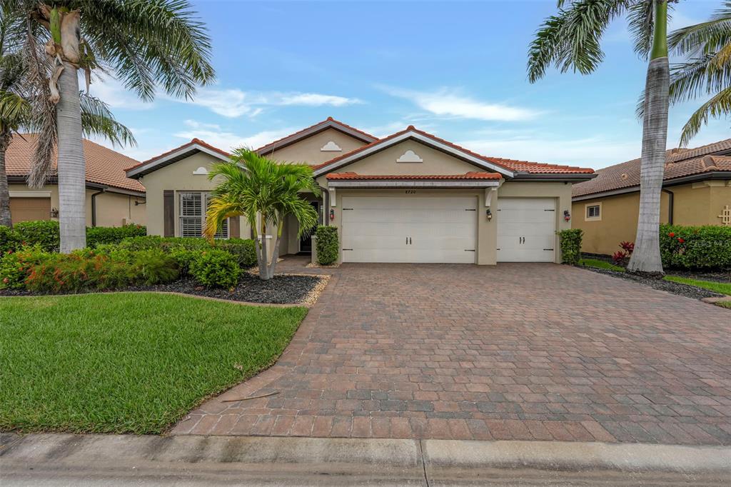 A single-story house with a brick paver driveway, three-car garage, and palm trees — 8720 WESTWOOD OAKS PLACE, FORT MYERS, FL
