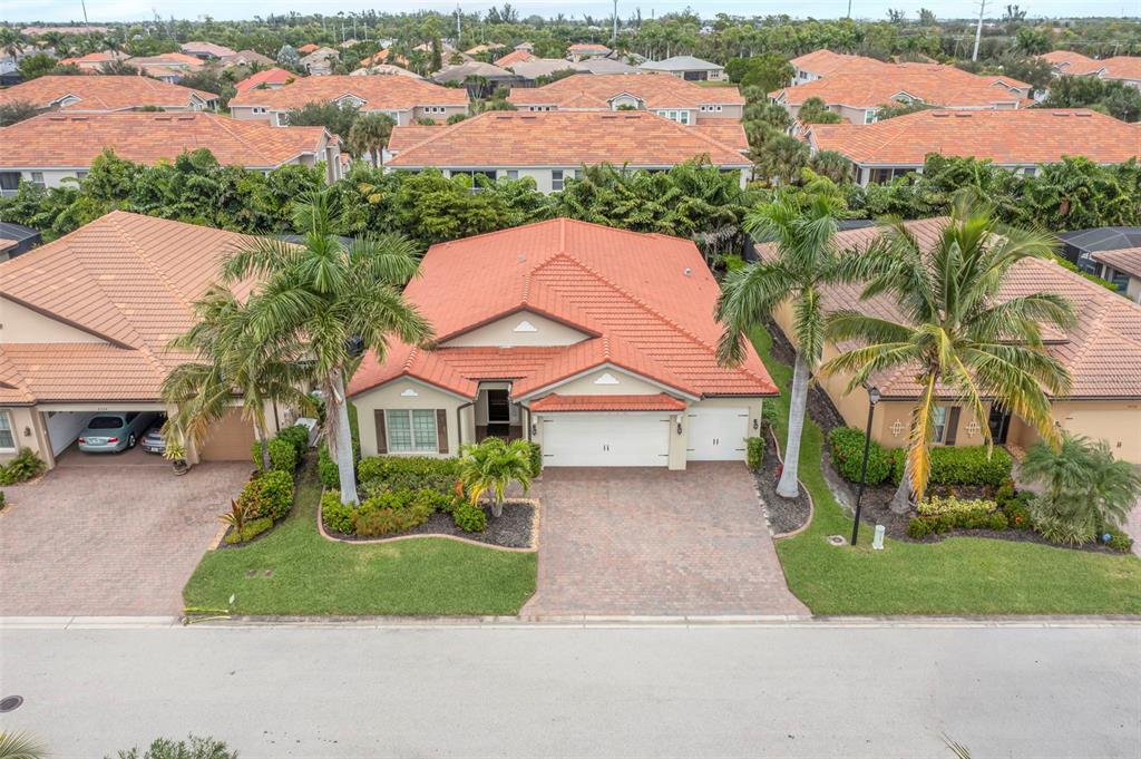 An aerial view shows a single-story house with a red tile roof and paved driveway — 8720 WESTWOOD OAKS PLACE, FORT MYERS, FL