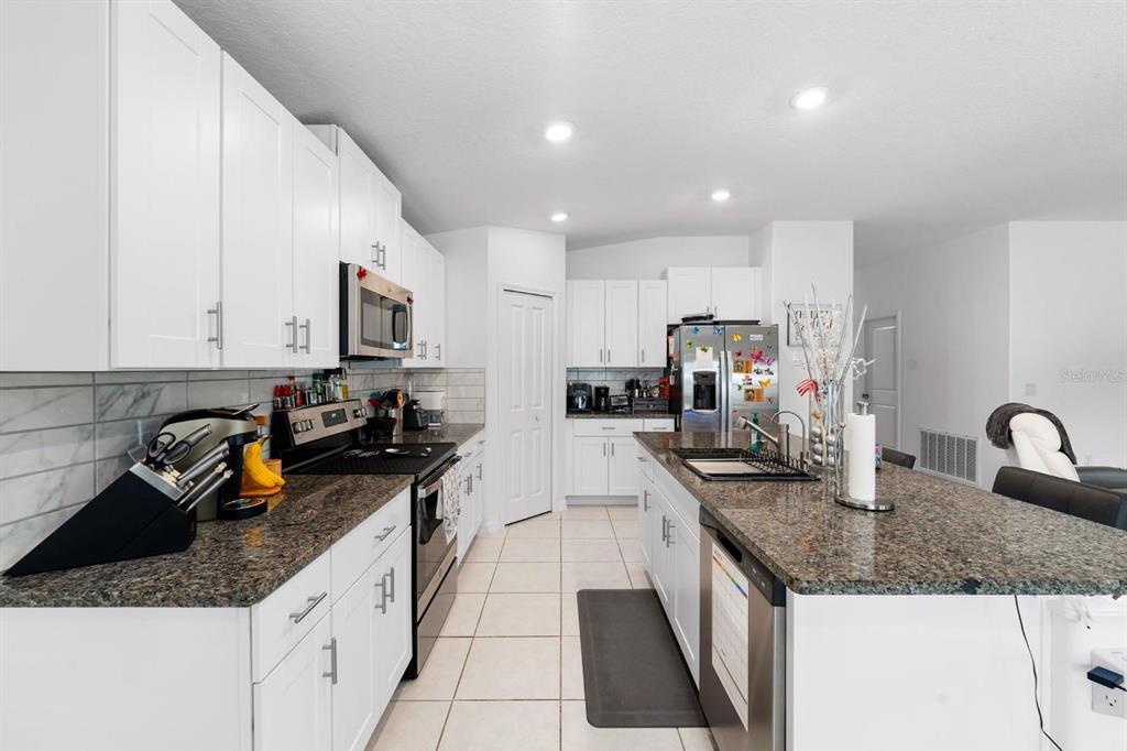 A kitchen with white cabinets, granite countertops, stainless steel appliances, and a central island — 32024 HAWTHORNE COTTAGE PLACE, SAN ANTONIO, FL