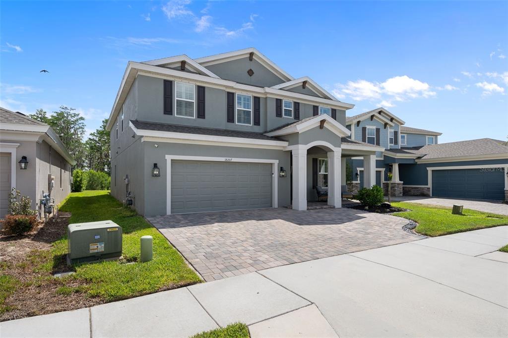 A two-story gray house with a paved driveway and a two-car garage — 18207 RAMBLE ON WAY, LAND O LAKES, FL