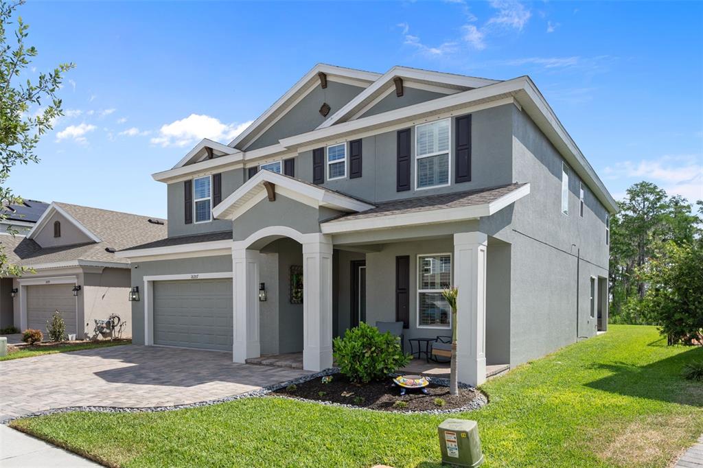A two-story gray stucco house with a paved driveway, front porch, and attached garage — 18207 RAMBLE ON WAY, LAND O LAKES, FL