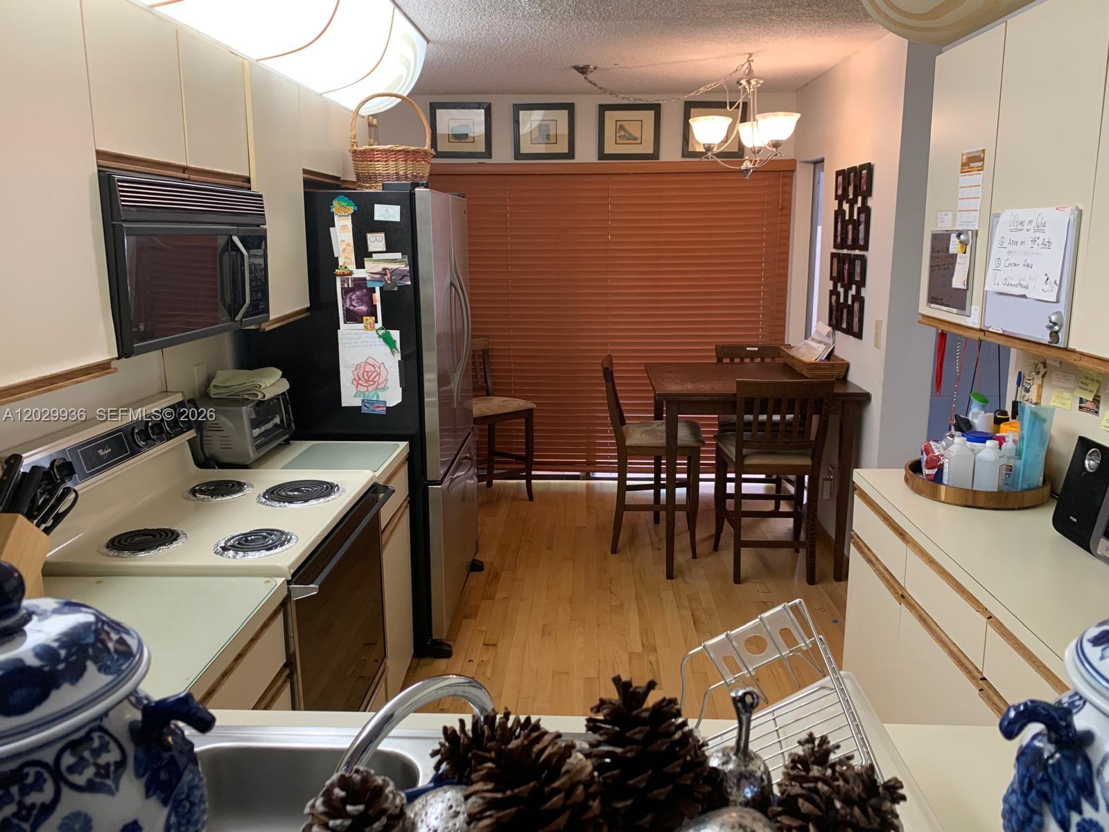 A kitchen with light-colored cabinets, stainless steel appliances, and a dining area by a window — 3340 Torremolinos Ave # 40, Doral FL 33178, DORAL, FL