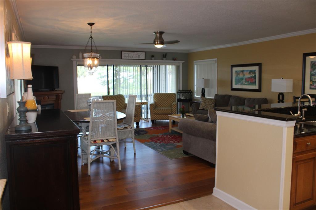 An open-concept living and dining area features hardwood floors, a ceiling fan, and sliding doors — 335 WINDRUSH LOOP UNIT 335, TARPON SPRINGS, FL