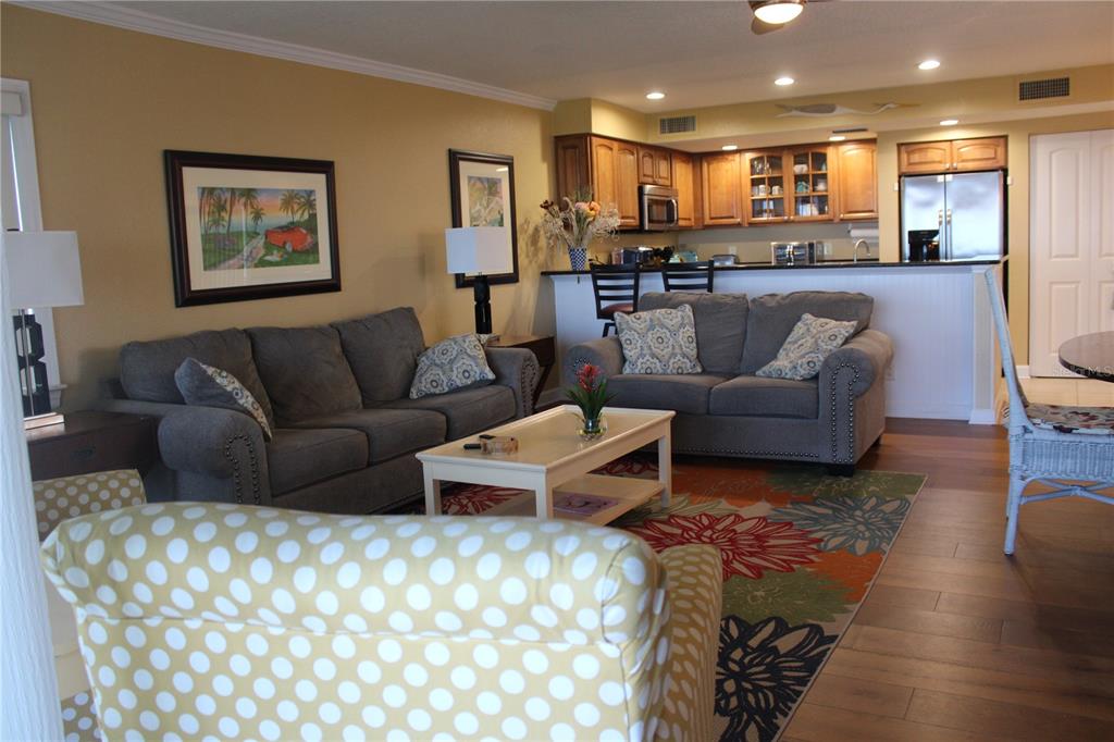 A living room with gray sofas, a patterned rug, and an open kitchen with wood cabinets — 335 WINDRUSH LOOP UNIT 335, TARPON SPRINGS, FL