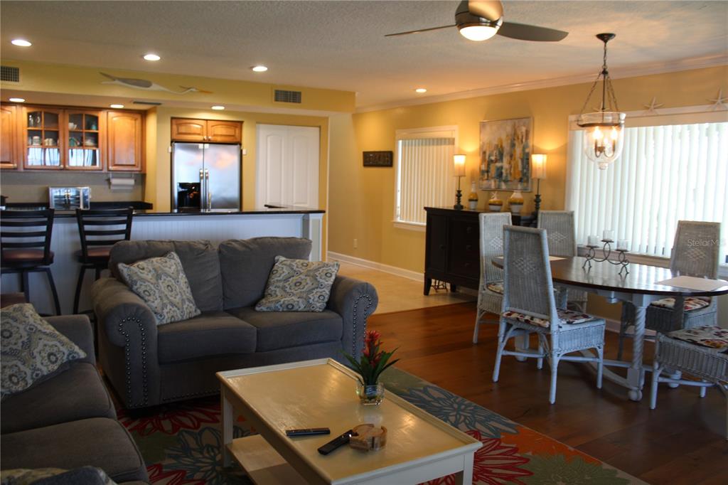 A living room and dining area feature hardwood floors, a gray sofa, and kitchen access — 335 WINDRUSH LOOP UNIT 335, TARPON SPRINGS, FL
