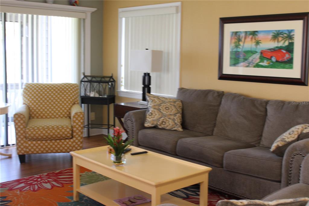 A living room features a grey sofa, a yellow patterned armchair, and a coffee table — 335 WINDRUSH LOOP UNIT 335, TARPON SPRINGS, FL