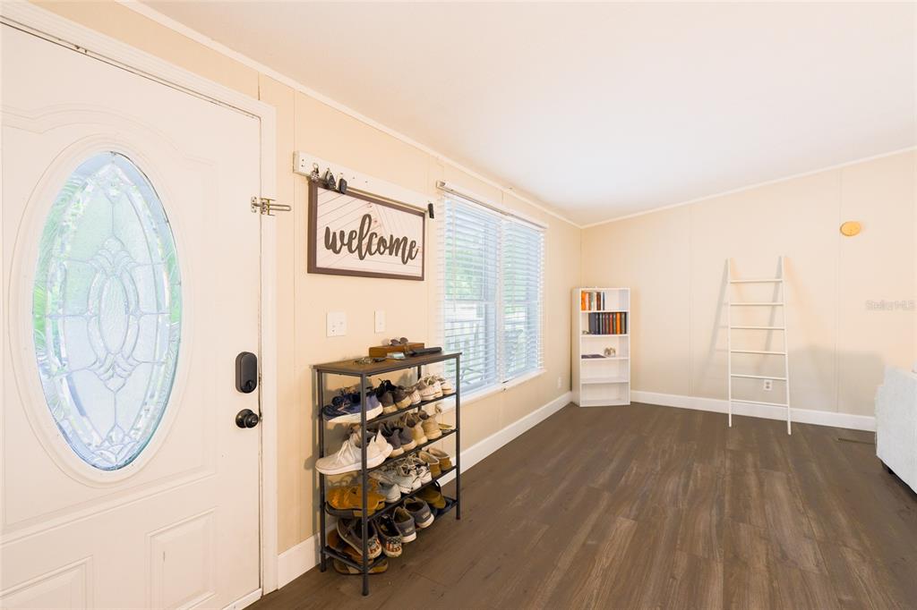 A bright entryway features a white front door, a shoe rack, and wood-look flooring — 1419 OSCEOLA HOLLOW ROAD, ODESSA, FL