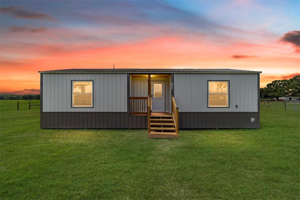 A single-story manufactured home with grey and brown siding sits in a grassy field — 1177 NW 102ND BOULEVARD, WILDWOOD, FL