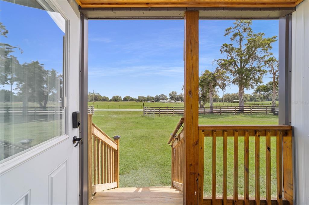 A view from a doorway looking out onto a grassy field with wooden fencing — 1177 NW 102ND BOULEVARD, WILDWOOD, FL