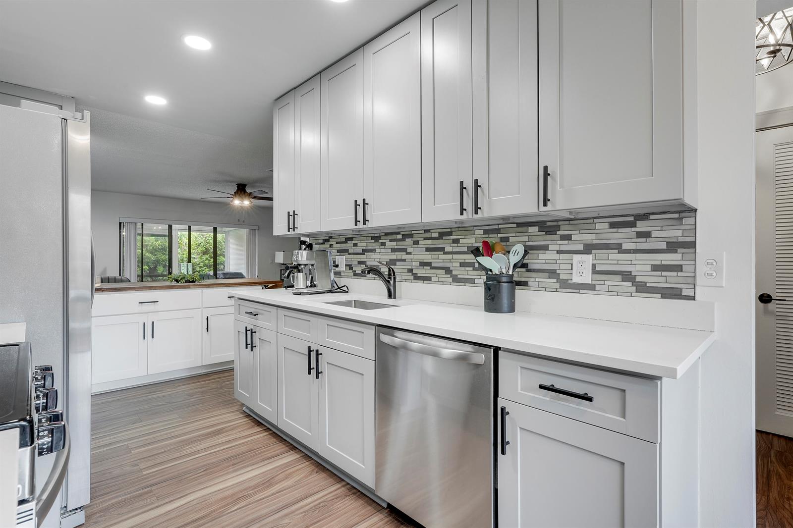 A kitchen features light gray cabinets, white countertops, a stainless steel dishwasher, and tiled backsplash — 21691 Cypress Road # 16c, Boca Raton FL 33433, BOCA RATON, FL