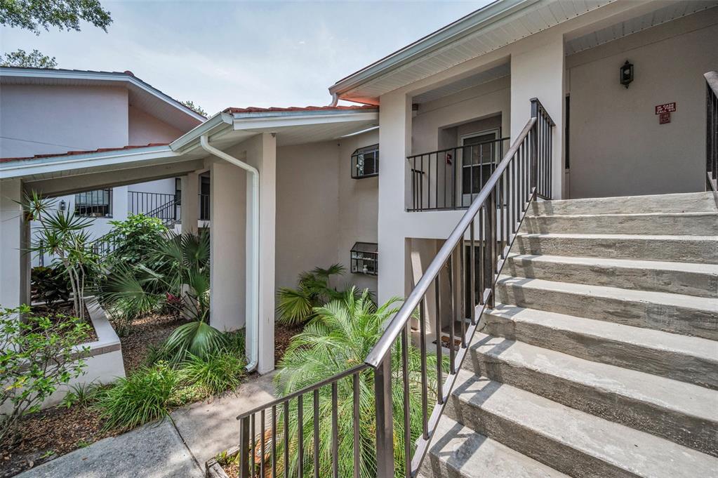 An outdoor concrete staircase leads to the second-floor entrance of a multi-story residential building — 300 S FLORIDA AVENUE UNIT 200J, TARPON SPRINGS, FL
