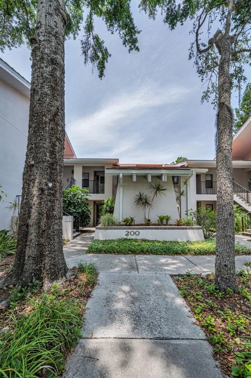 A concrete walkway leads to the entrance of a two-story apartment building labeled number 200 — 300 S FLORIDA AVENUE UNIT 200J, TARPON SPRINGS, FL