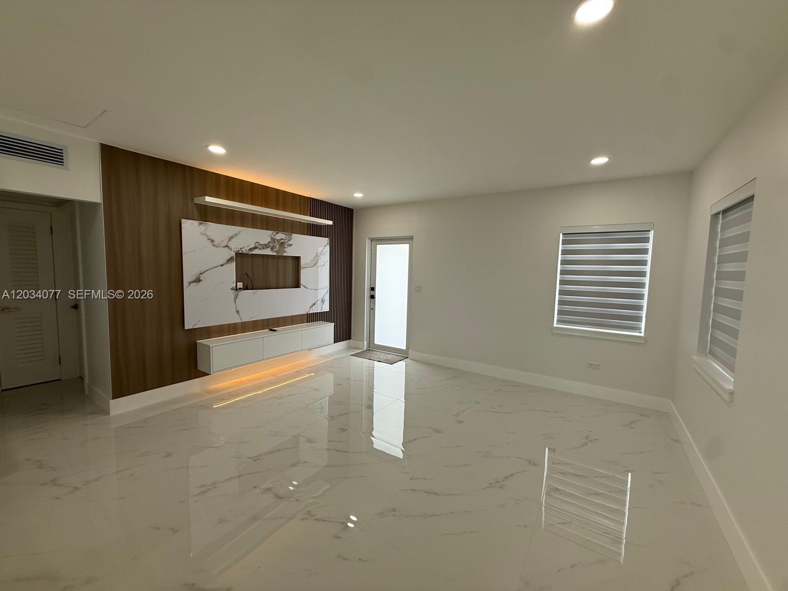 A living room features white marble floors, a wood-paneled accent wall, and a floating console — 521 E 33rd St, Hialeah FL 33013, HIALEAH, FL