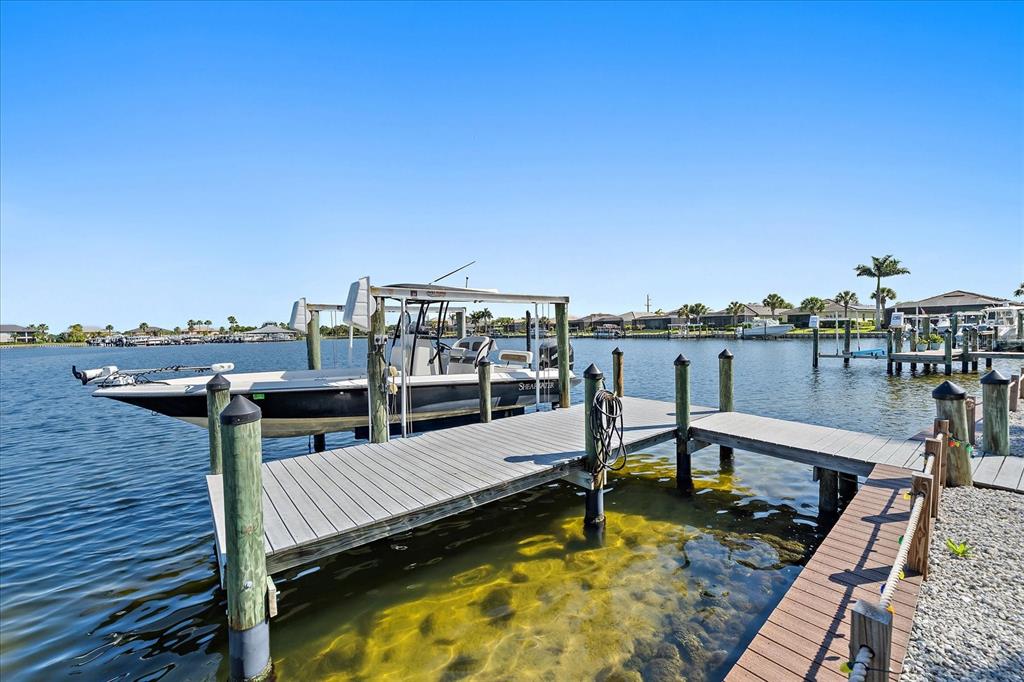 A boat is docked at a wooden pier on a canal near residential homes — 5040 LAKE OVERLOOK AVENUE, BRADENTON, FL