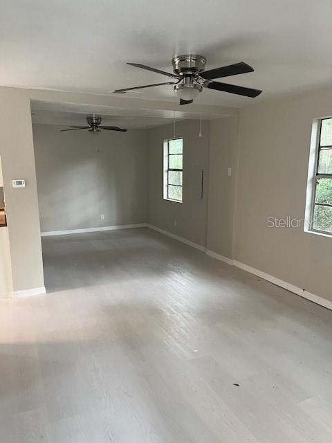 An interior view shows a living area with light-colored flooring, beige walls, and two ceiling fans — 25317 NW 6TH AVENUE, NEWBERRY, FL