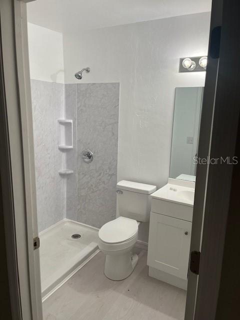 A small bathroom features a white vanity, a toilet, and a walk-in shower with tile — 25317 NW 6TH AVENUE, NEWBERRY, FL