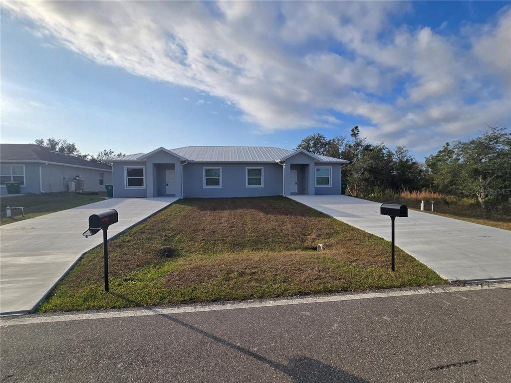 A grey duplex with a metal roof, two concrete driveways, and two black mailboxes — 29469 PEACE RIVER SHORES BOULEVARD, PUNTA GORDA, FL