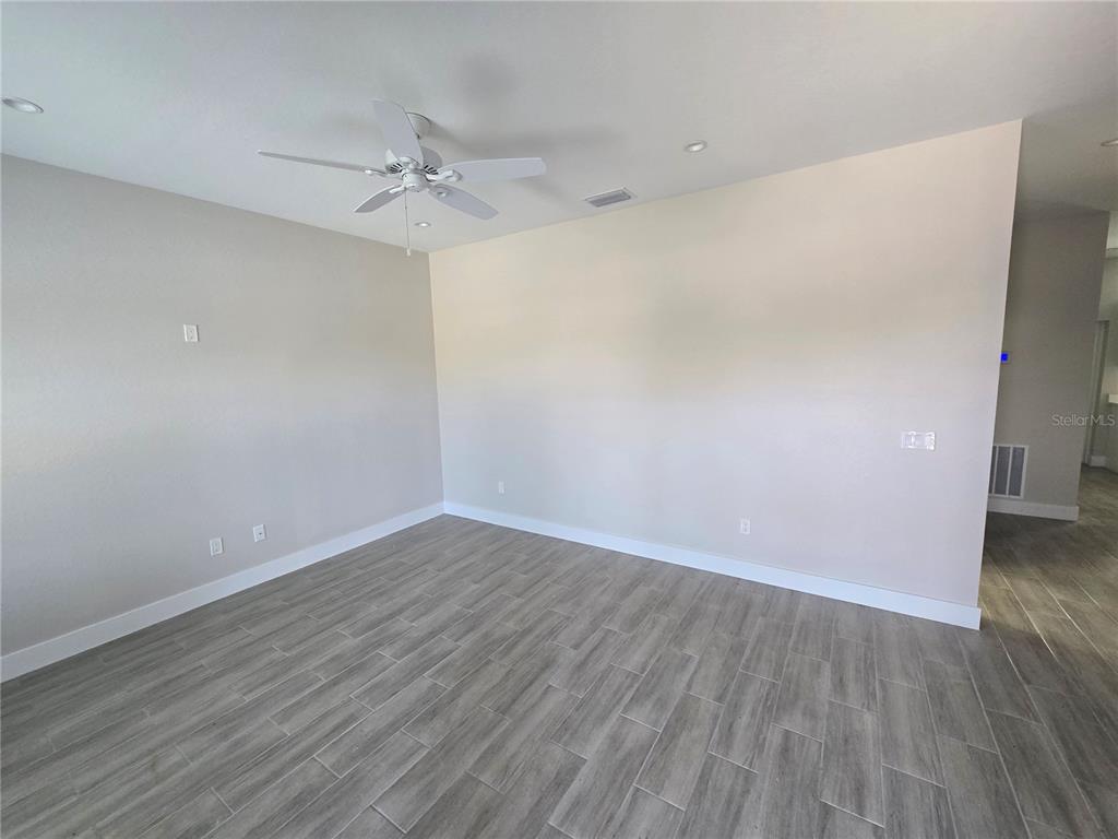 An empty room features light-colored walls, a ceiling fan, and gray wood-look tile flooring — 29469 PEACE RIVER SHORES BOULEVARD, PUNTA GORDA, FL