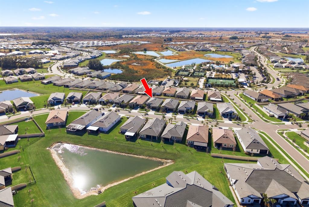 An aerial view shows a residential neighborhood with a red arrow pointing to a house — 10661 TUPPER CAY DRIVE, SAN ANTONIO, FL