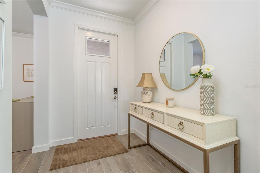 A bright entryway features a white door, a console table with a lamp, and a mirror — 10661 TUPPER CAY DRIVE, SAN ANTONIO, FL