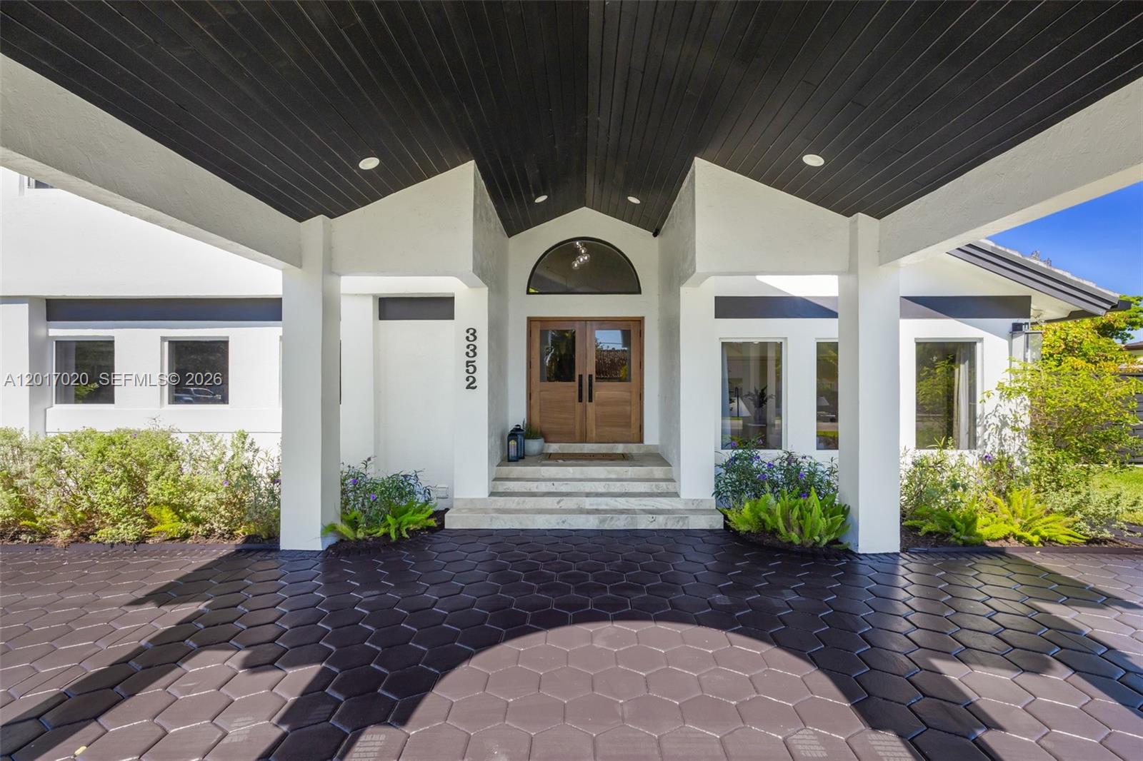 A covered entryway features a dark hexagonal paver driveway and a wooden double front door — 3352 SW 110th Ave, Miami FL 33165, MIAMI, FL