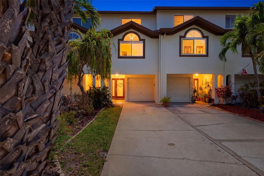 A two-story townhouse exterior with a concrete driveway, two garages, and arched upper windows — 381 MADEIRA CIRCLE, TIERRA VERDE, FL