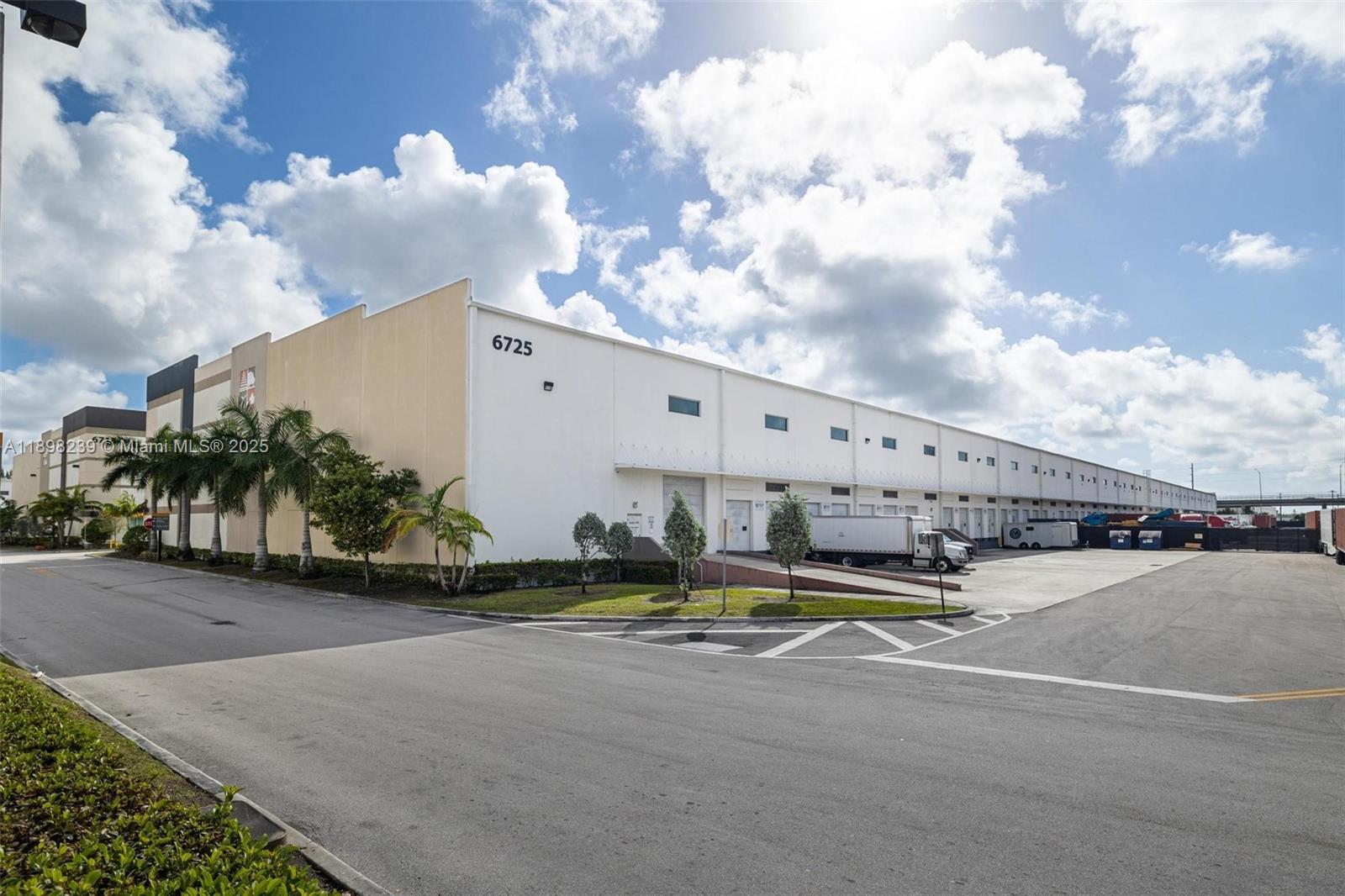 A large industrial warehouse building features a white exterior, multiple loading docks, and palm trees — 6725 NW 36th St, Miami FL 33166, MIAMI, FL