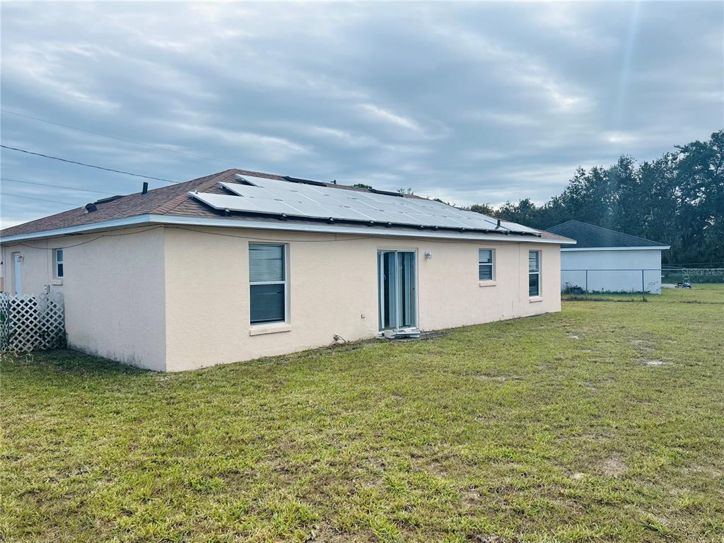 The exterior of a single-story house with a solar panel array on the roof — 1731 MINNOW COURT, POINCIANA, FL