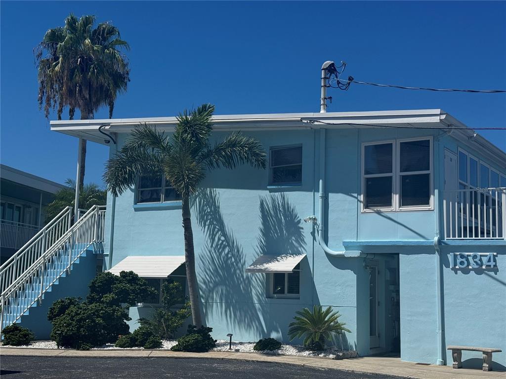 A light blue two-story building features a palm tree, white railings, and an exterior staircase — 1834 SHORE DRIVE S UNIT 6, SOUTH PASADENA, FL