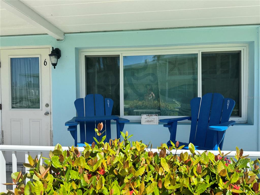 Two blue Adirondack chairs sit on a light blue porch in front of a window — 1834 SHORE DRIVE S UNIT 6, SOUTH PASADENA, FL