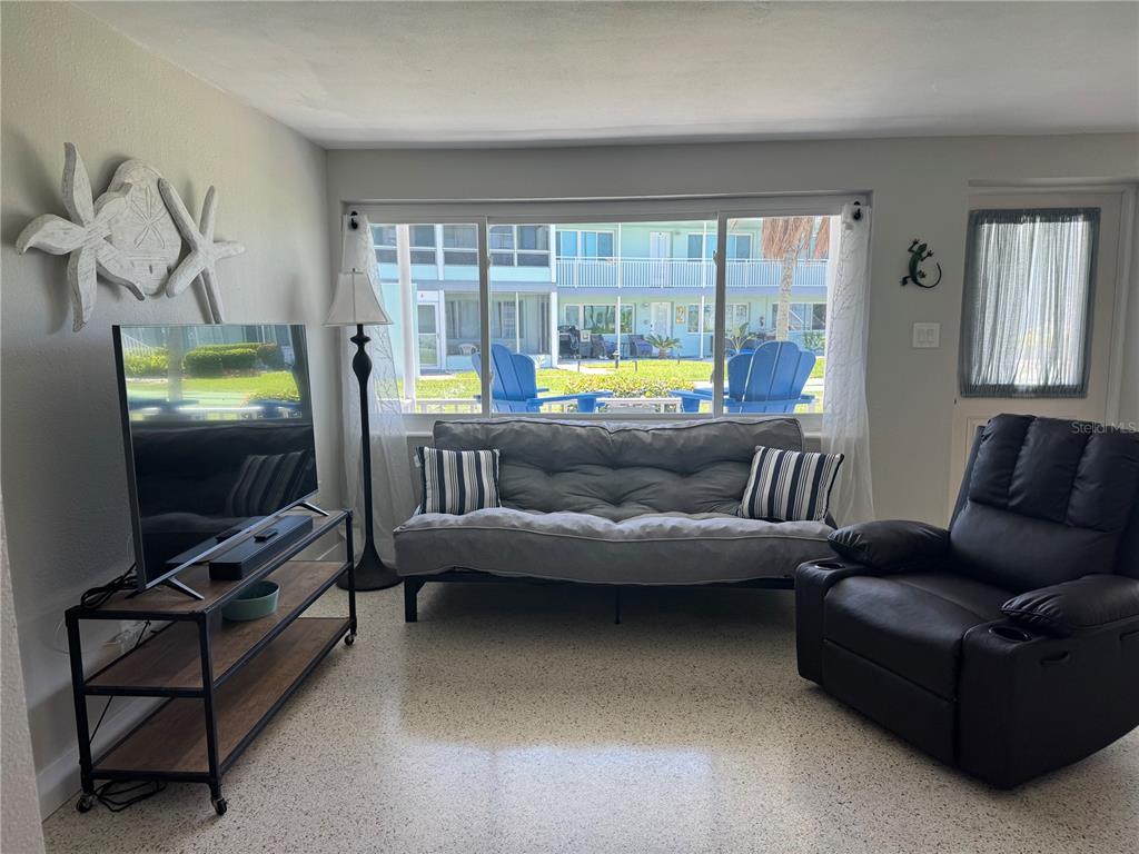 A living room features a gray futon, a black recliner, and a large window view — 1834 SHORE DRIVE S UNIT 6, SOUTH PASADENA, FL